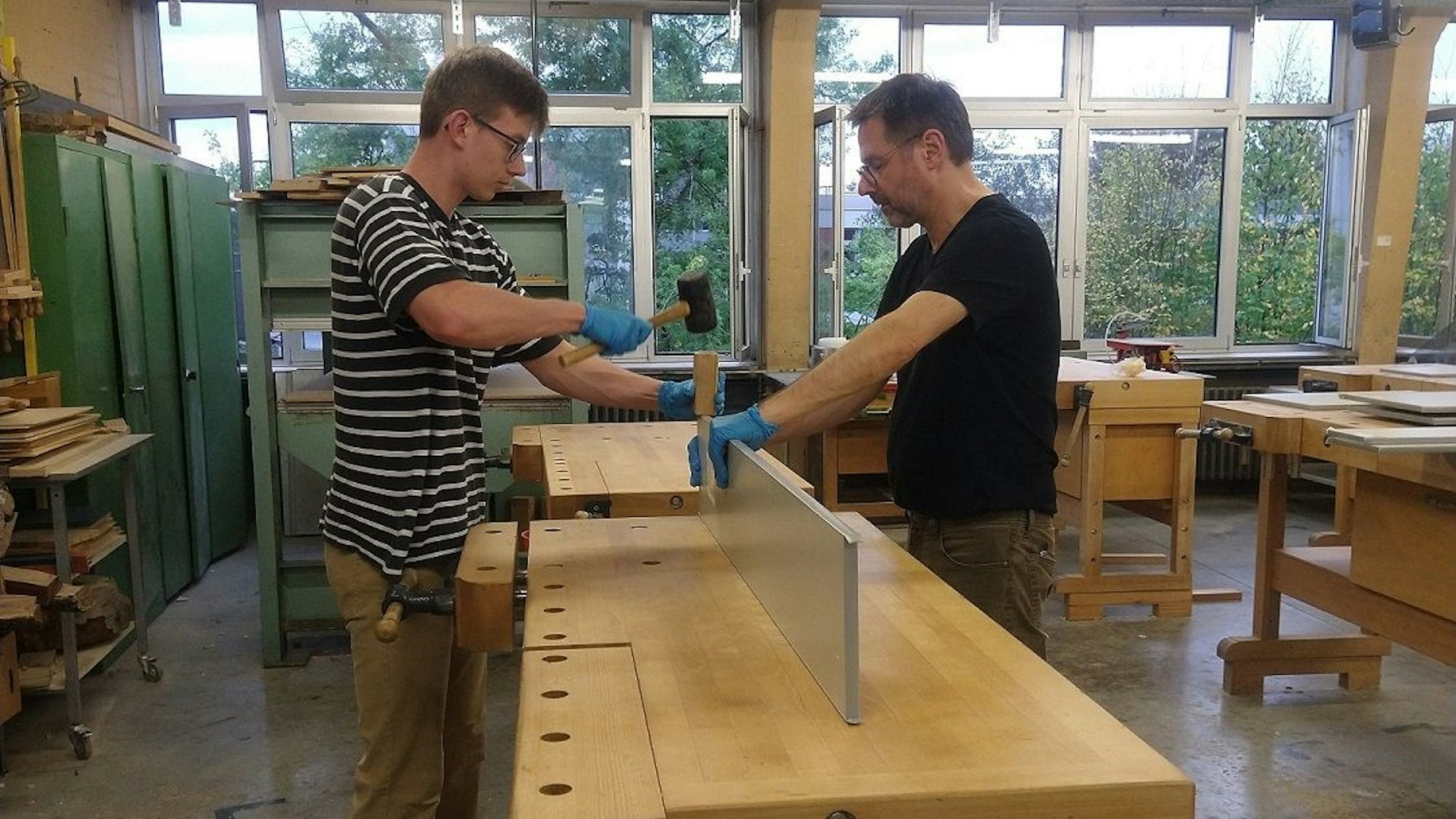 Auf einer Werkbank ummanteln mit Männer die Kanten eines Brettes.