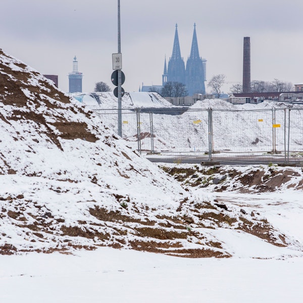Der Kölner Dom schimmert hinter einer schneebedeckten Landschaft.