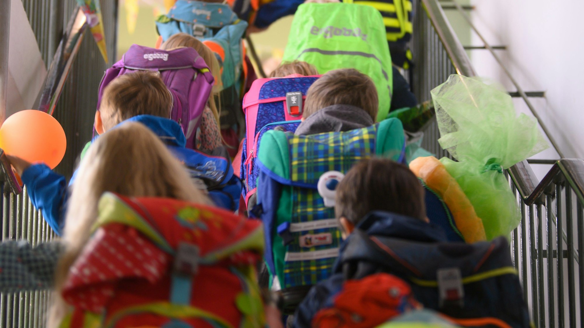 Grundschüler einer ersten Klasse laufen die Treppe rauf zu ihrem Klassenzimmer.