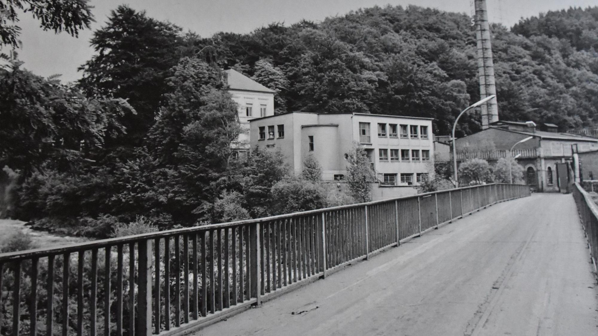 Ein Bild in schwarzweiß zeigt eine Brücke und mehrere Gebäude.