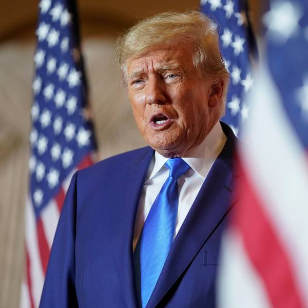 Es ist Trump zu sehen, der hinter einer US-amerikanischen Flagge steht.