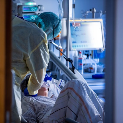Ein Pfleger kümmert sich in Schutzausrüstung um eine Patientin, die beatmet wird.