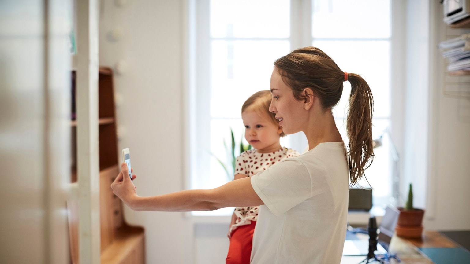 Influencerin nimmt ein Selfie mit ihrer Tochter auf Symbolbild.
