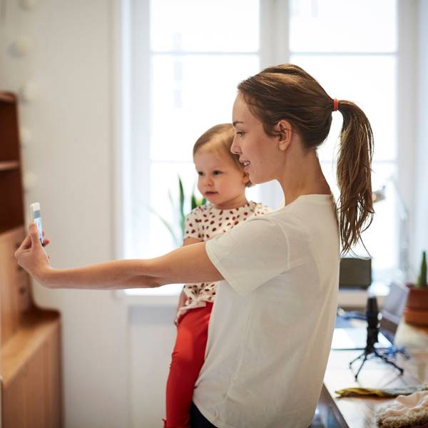 Influencerin nimmt ein Selfie mit ihrer Tochter auf Symbolbild.