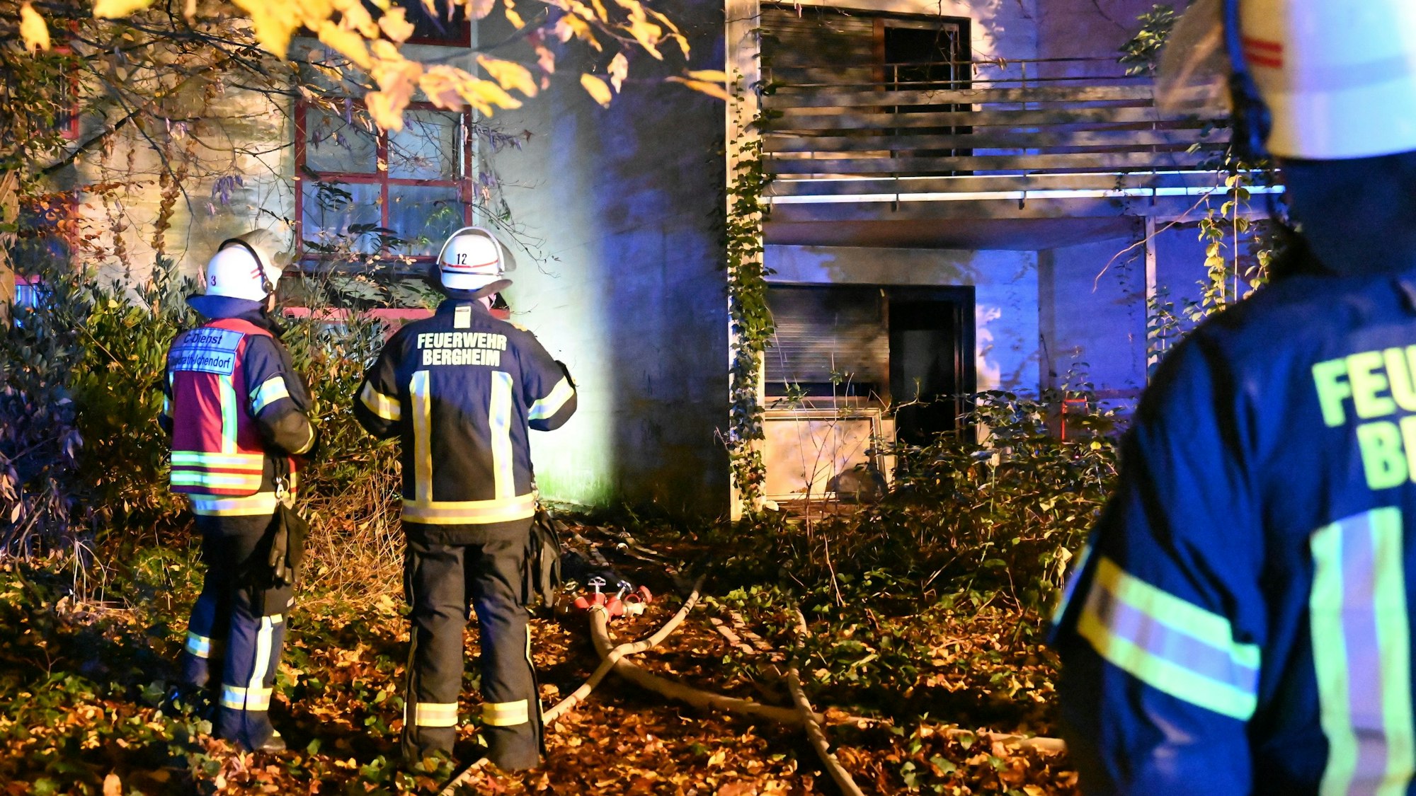 Feuerwehrleute stehen vor dem brennenden Haus in Bergheim-Ahe.