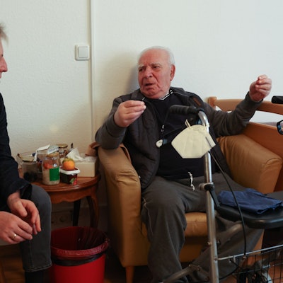 Metin Türköz sitzt in einem Ledersessel und gestikuliert, Nedim Hazar sitzt neben ihm und hört interessiert zu.