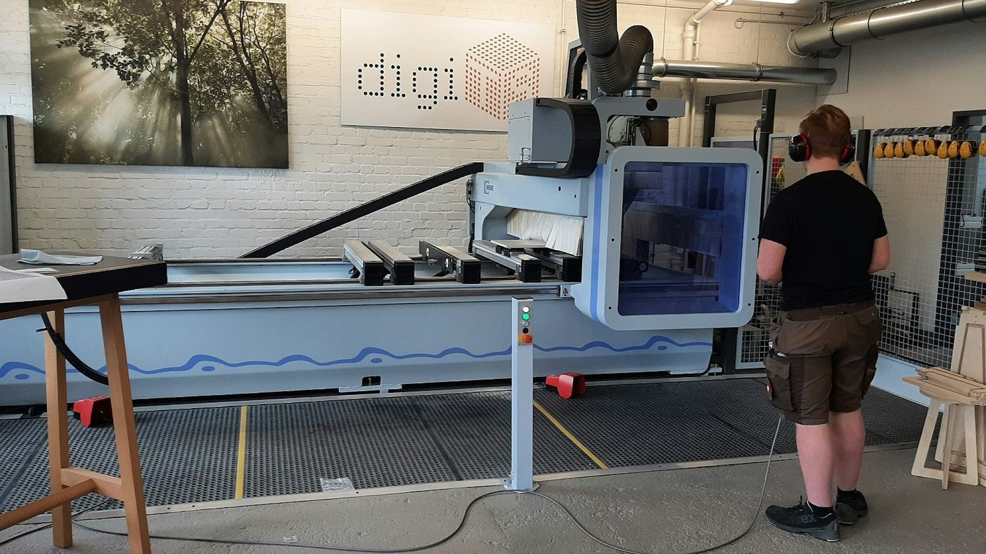 Ein Tischlerazubi ist von hinten zu sehen und arbeitet an einer CNC-Fräse.