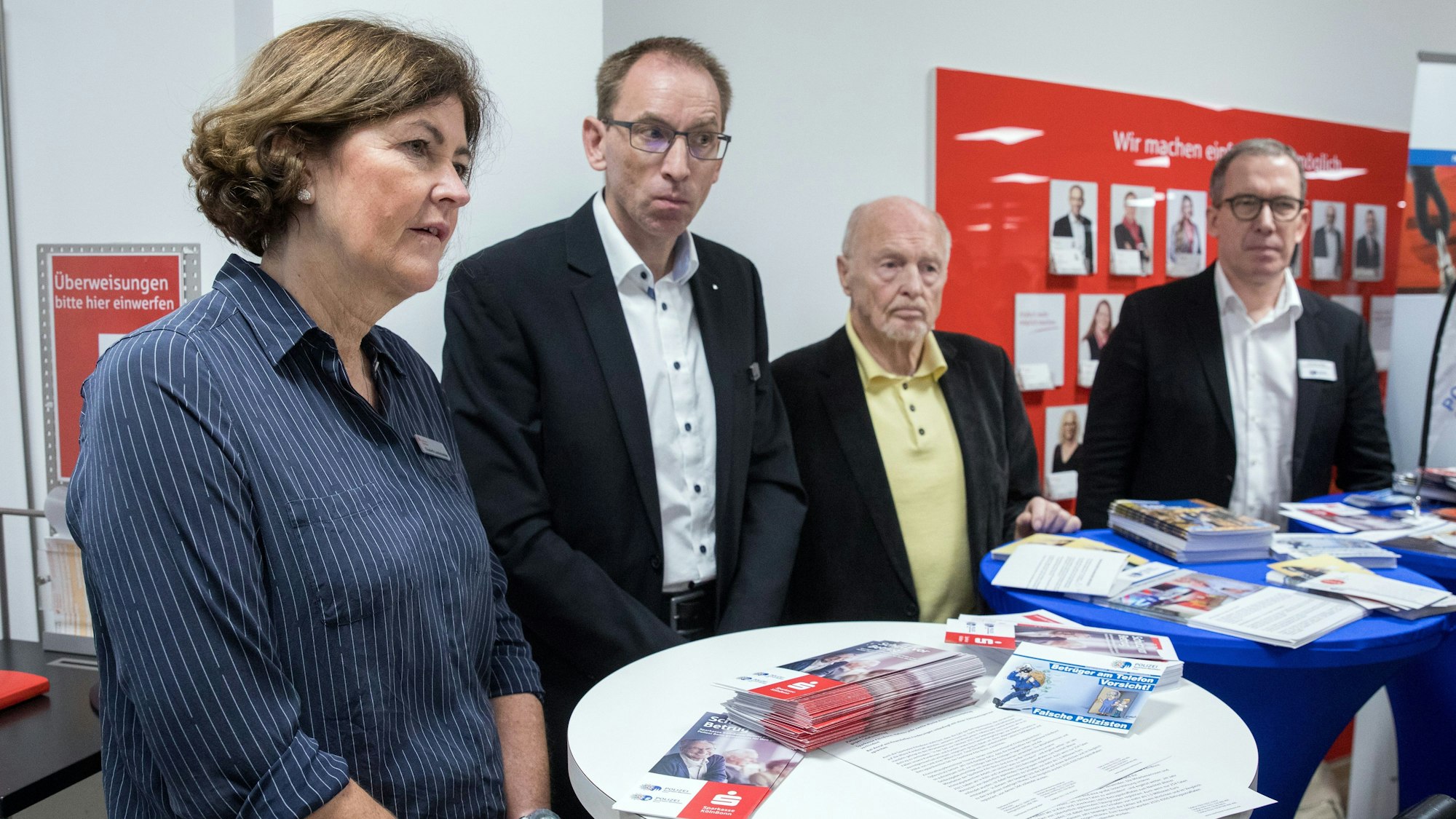 Pressekonferenz der Sparkasse KölnBonn und der Polizei zum Thema "Telefonbetrug".
Im Bild stehen von links nach rechts: Elisabeth Landschneider, Andreas Zindt, Gunther Nogge und Thomas Jansen. Vor ihnen sind Stehtische mit Infobroschüren aufgestellt.