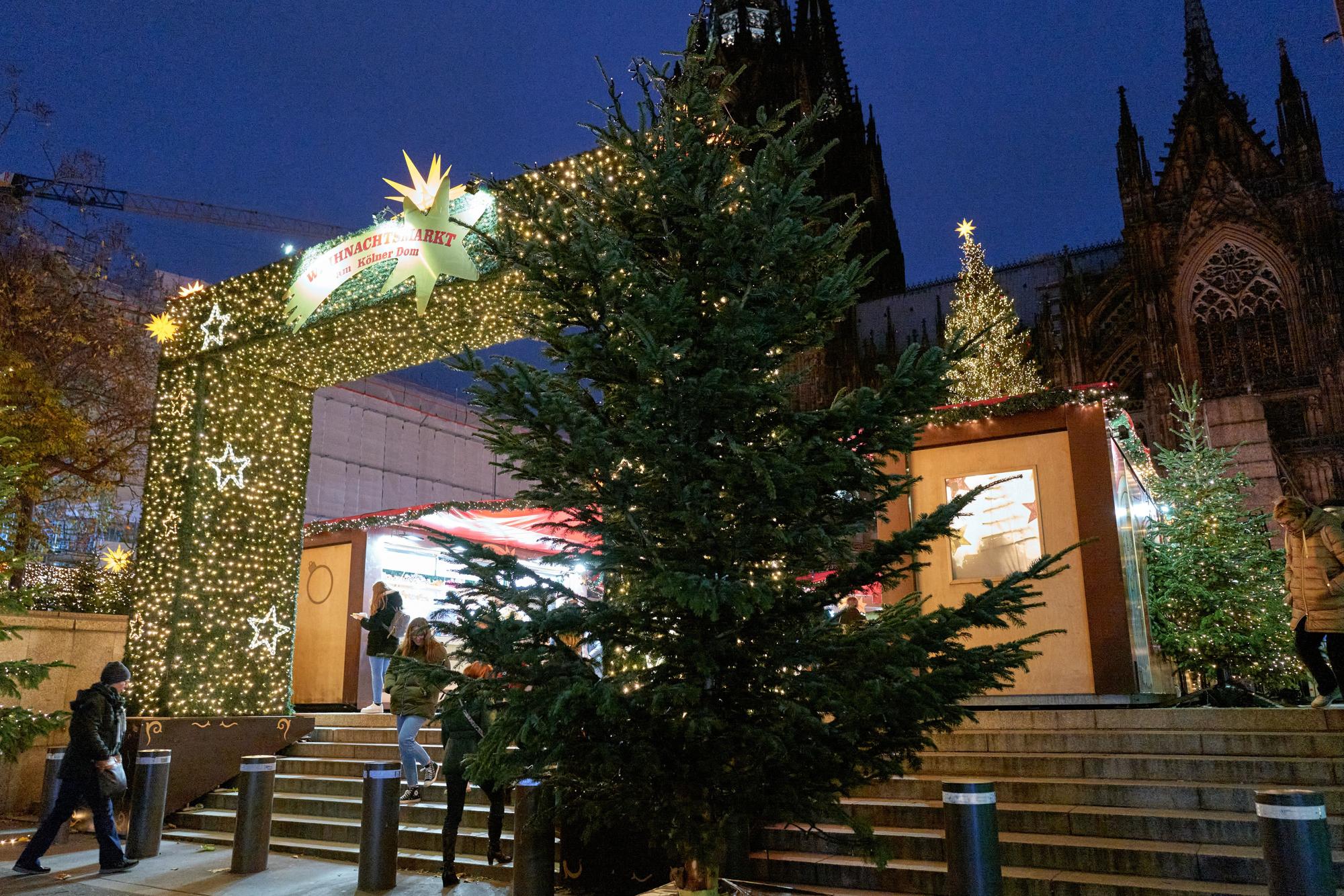 Ein hell erleuchteter Bogen ist der Eingang zum Weihnachtsmarkt auf der Domplatte. Davor steht ein Weihnachtsbaum.