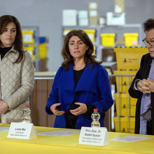 Bei einer Pressekonferenz des Blau-Gelben Kreuzes e.V. stehen Iryna Shum, Linda Mai und Dr. Detlef Bernd Gysanan einem Tisch, dahinter sind Pakete zu sehen.