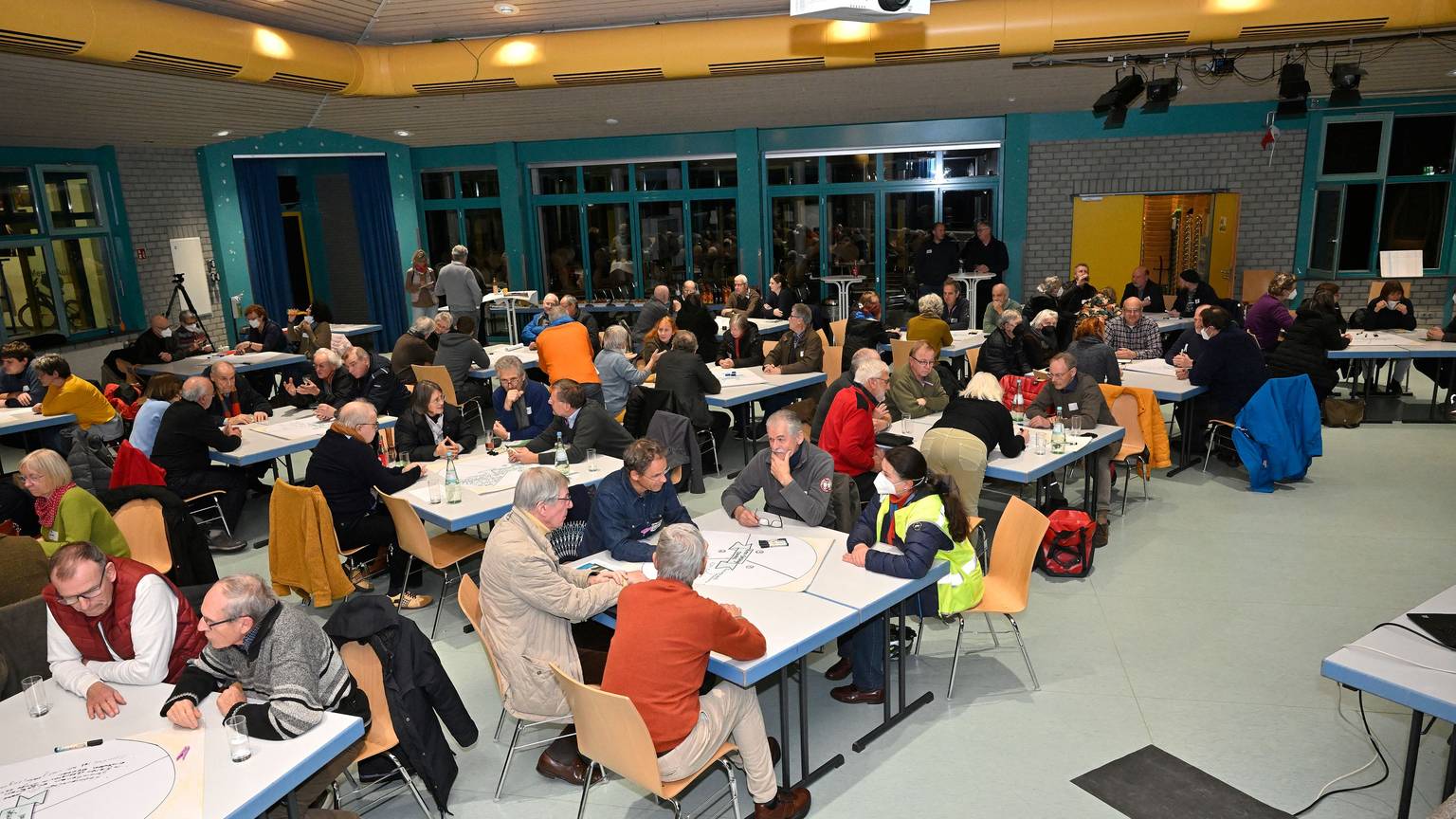 Viele Menschen sitzen an Tischen und unterhalten sich.