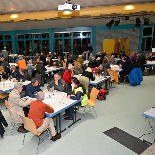 Viele Menschen sitzen an Tischen und unterhalten sich.