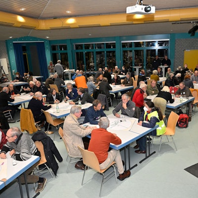 Viele Menschen sitzen an Tischen und unterhalten sich.