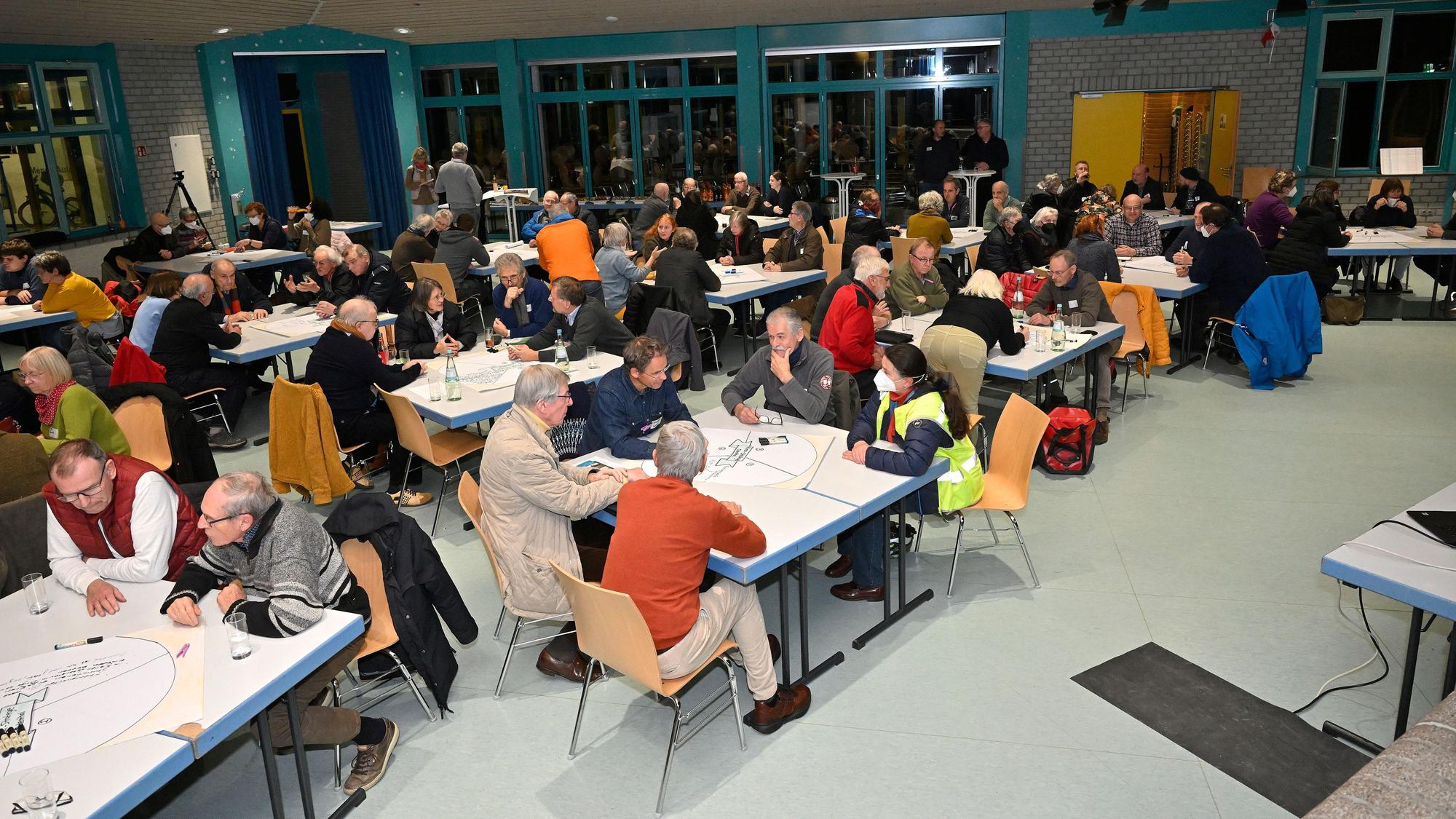Viele Menschen sitzen an Tischen und unterhalten sich.