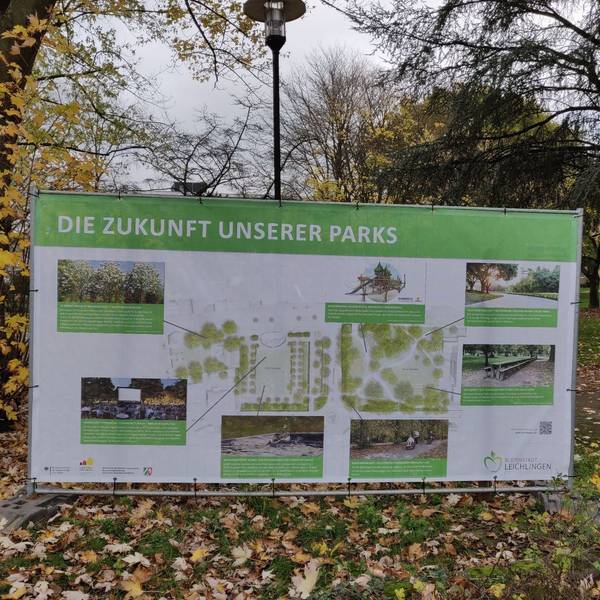 Ein großes Transparent mit Fotos, Planskizzen und Erläuterungen zur Umgestaltung steht an der Baustelle im Leichlinger Stadtpark.