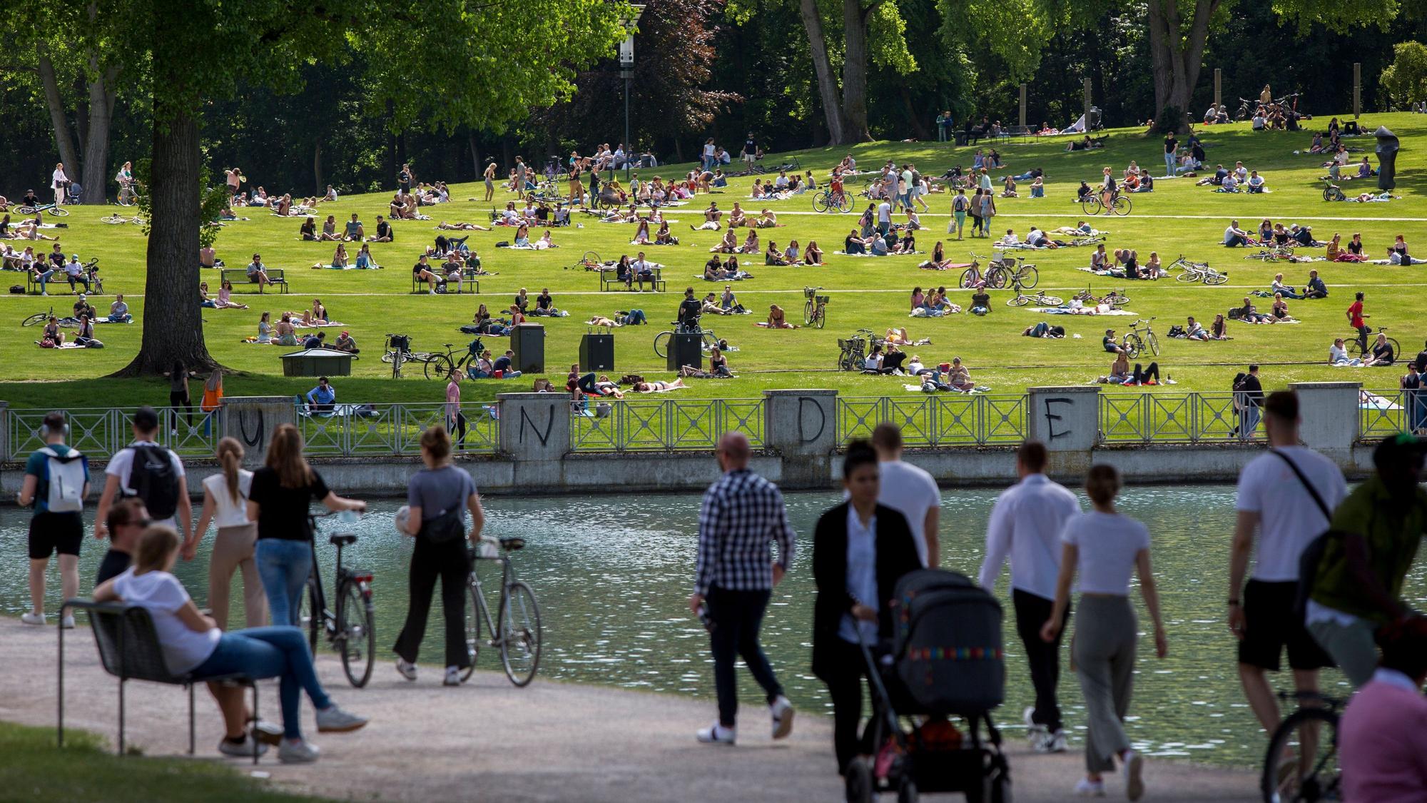 Menschen spazieren und sonnen sich am Aachener Weiher in Köln.