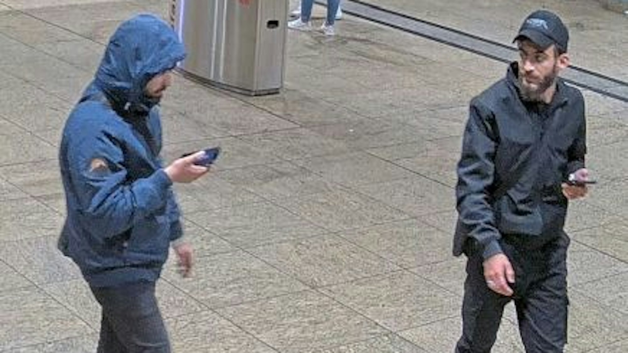 Zwei Tatverdächtige mit Handys in der Hand.