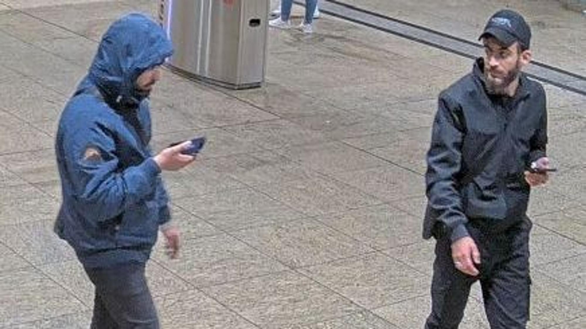 Zwei Tatverdächtige mit Handys in der Hand.