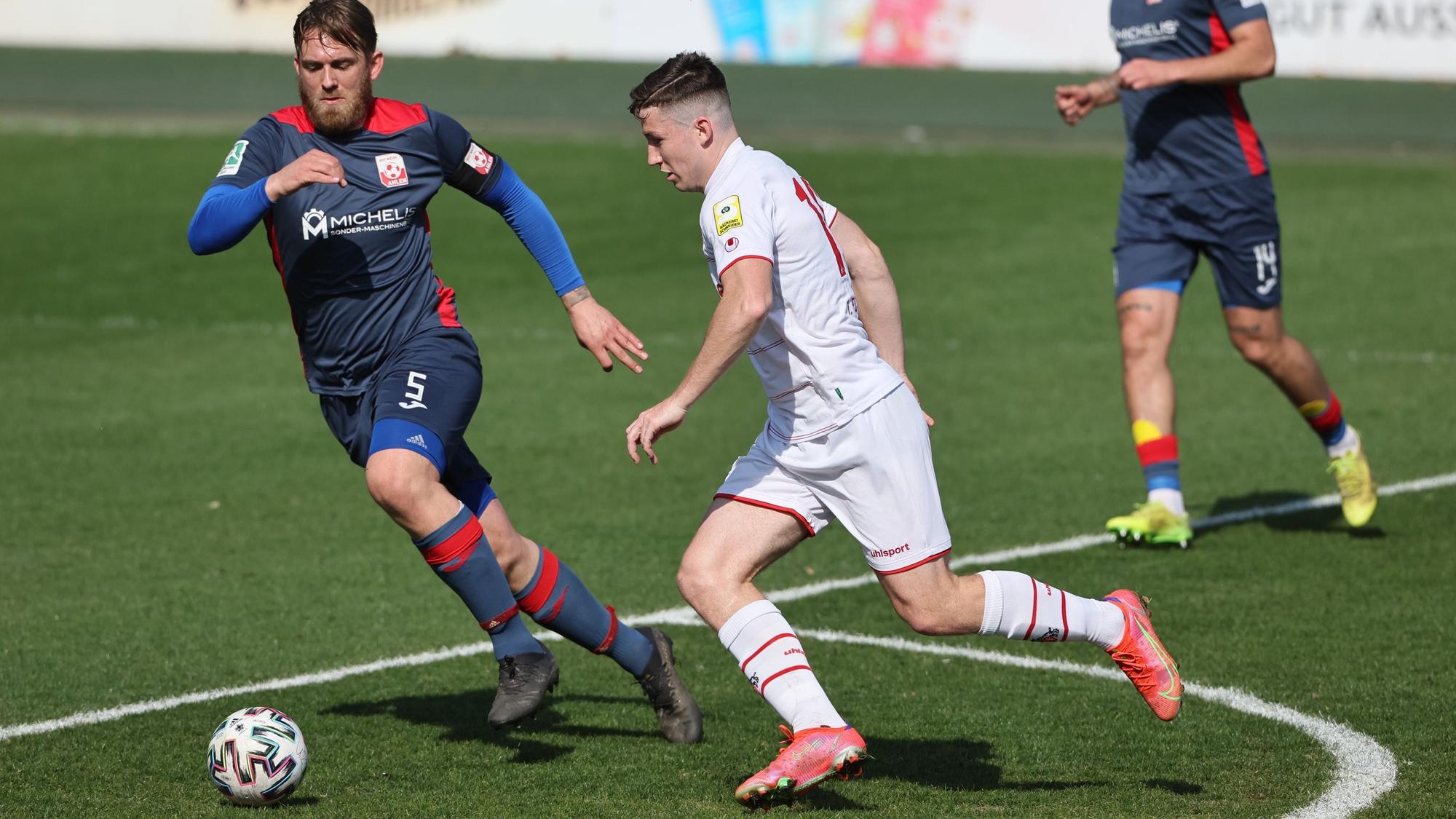 Ein Fußballspieler geht ins Laufduell mit seine Gegner.
