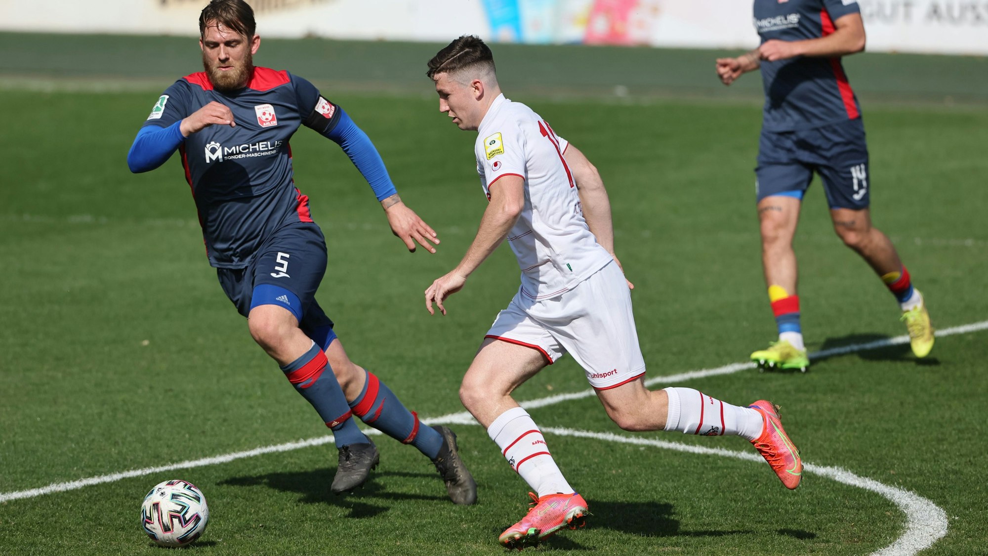 Ein Fußballspieler geht ins Laufduell mit seine Gegner.