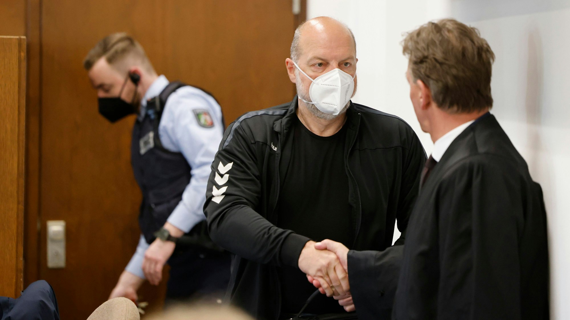 Der Angeklagte Thomas Drach begrüßt seinen Anwalt Andreas Kerkhof im Gerichtssaal des Landgerichts Köln.