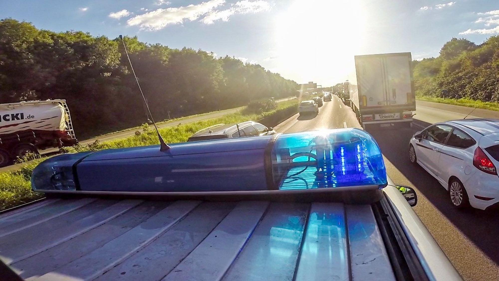Ein Streifenwagen der Autobahnpolizei Köln fährt mit Blaulicht und Martinshorn über die Autobahn.