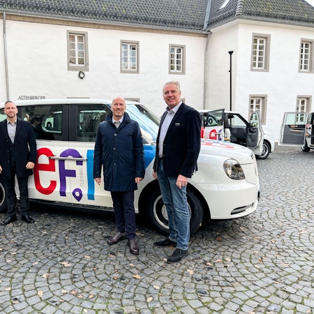 Menschen stehen in Odenthal-Altenberg vor einem Auto mit der Aufschrift „efi“.