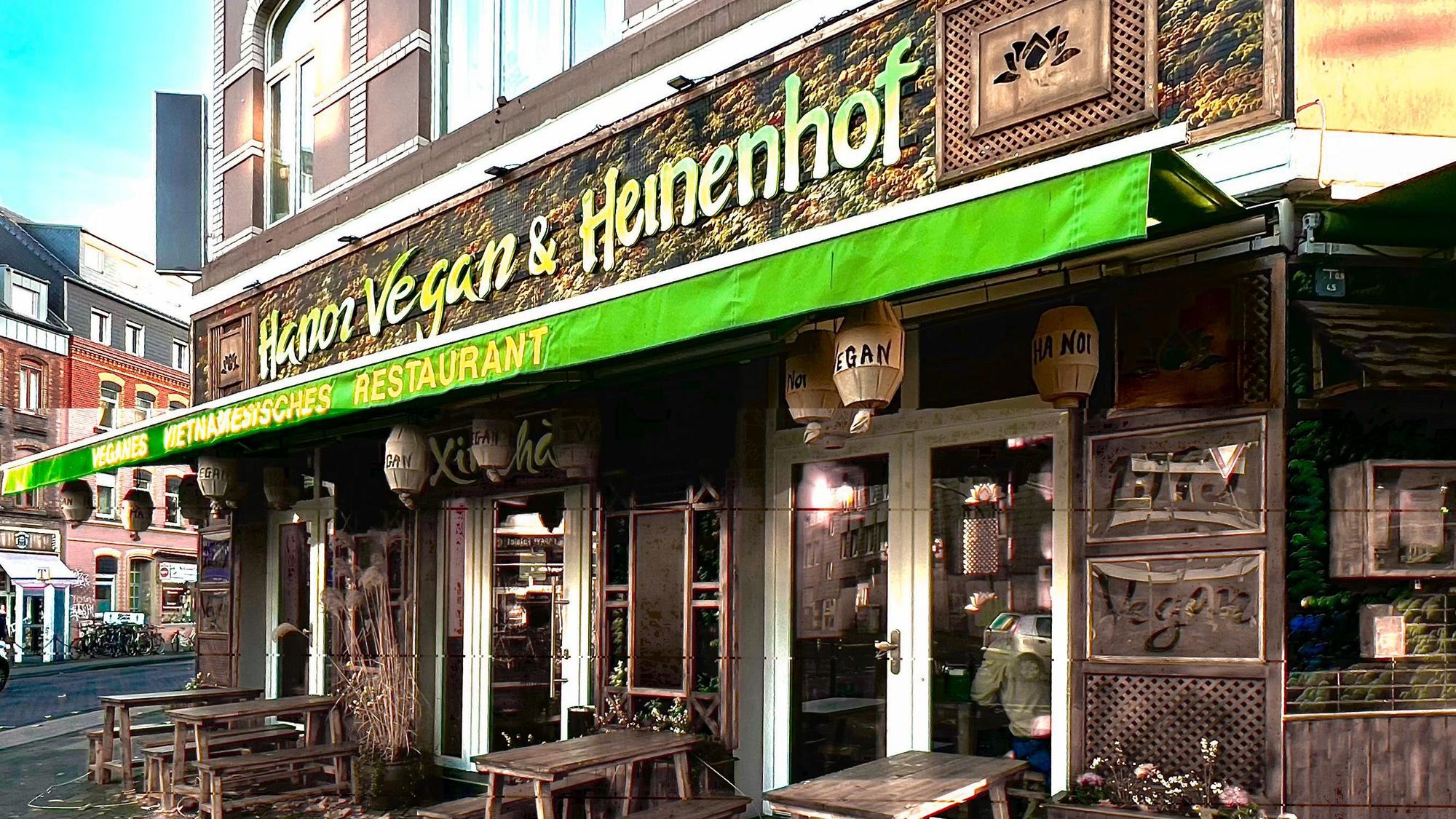 Eine grüne Markise hängt an einem Eckhaus, das eine asiatisch anmutende Fassade mit Holzornamenten hat.