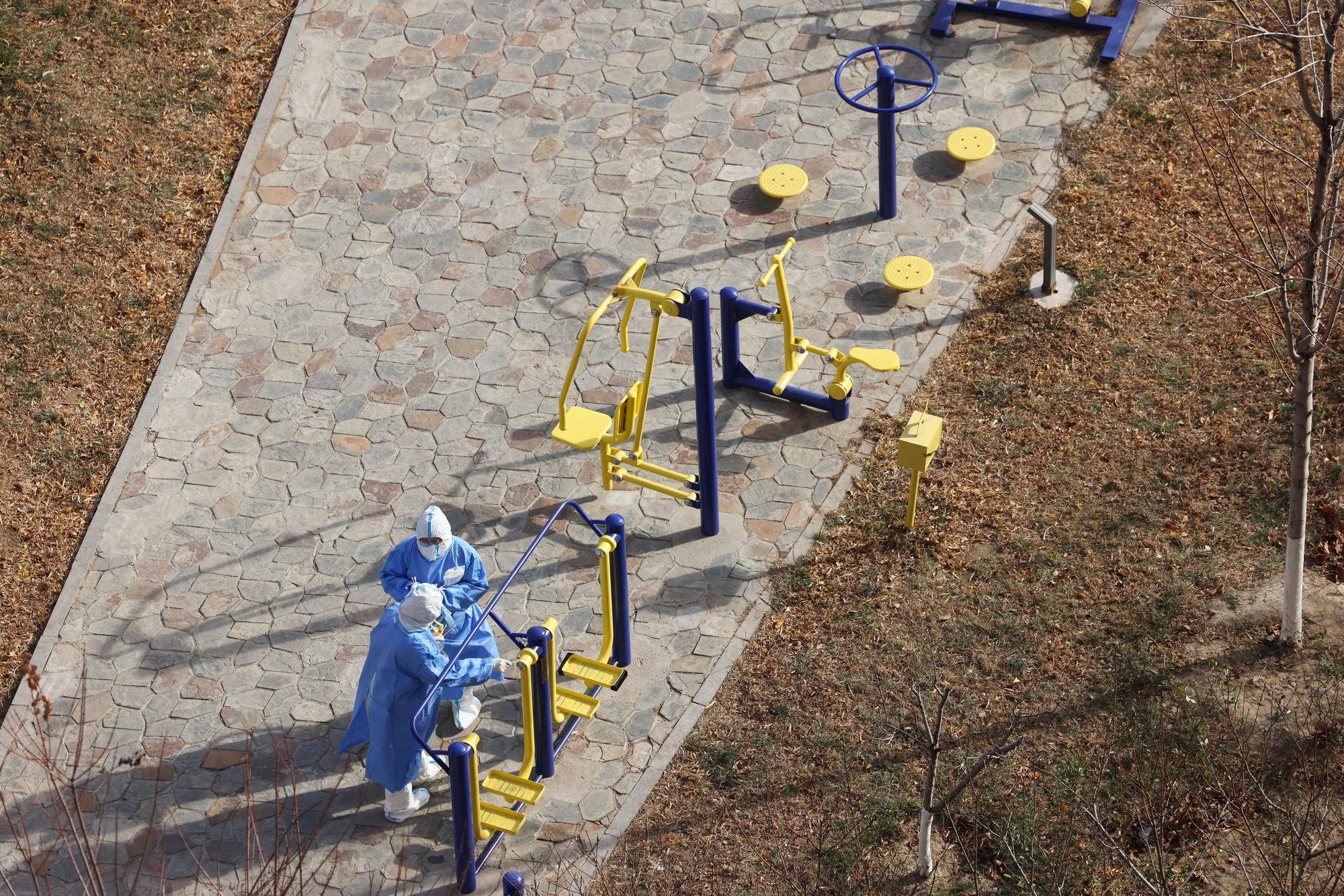 Chinesische medizinische Mitarbeiter nehmen Corona-Proben an einem Spielplatz.