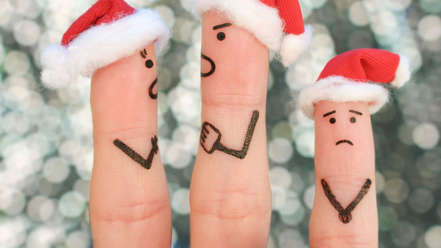 Finger mit Weihnachtsmannmützen und aufgemalten Gesichtern als streitendes Paar mit weinendem Kind.