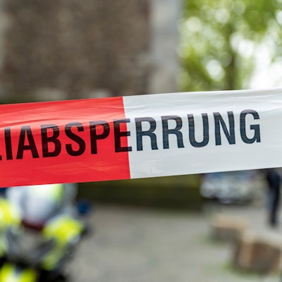 Ein mit Flatterband der Polizei NRW, dahinter ist verschwommen ein Polizei-Motorrad zu erkennen.