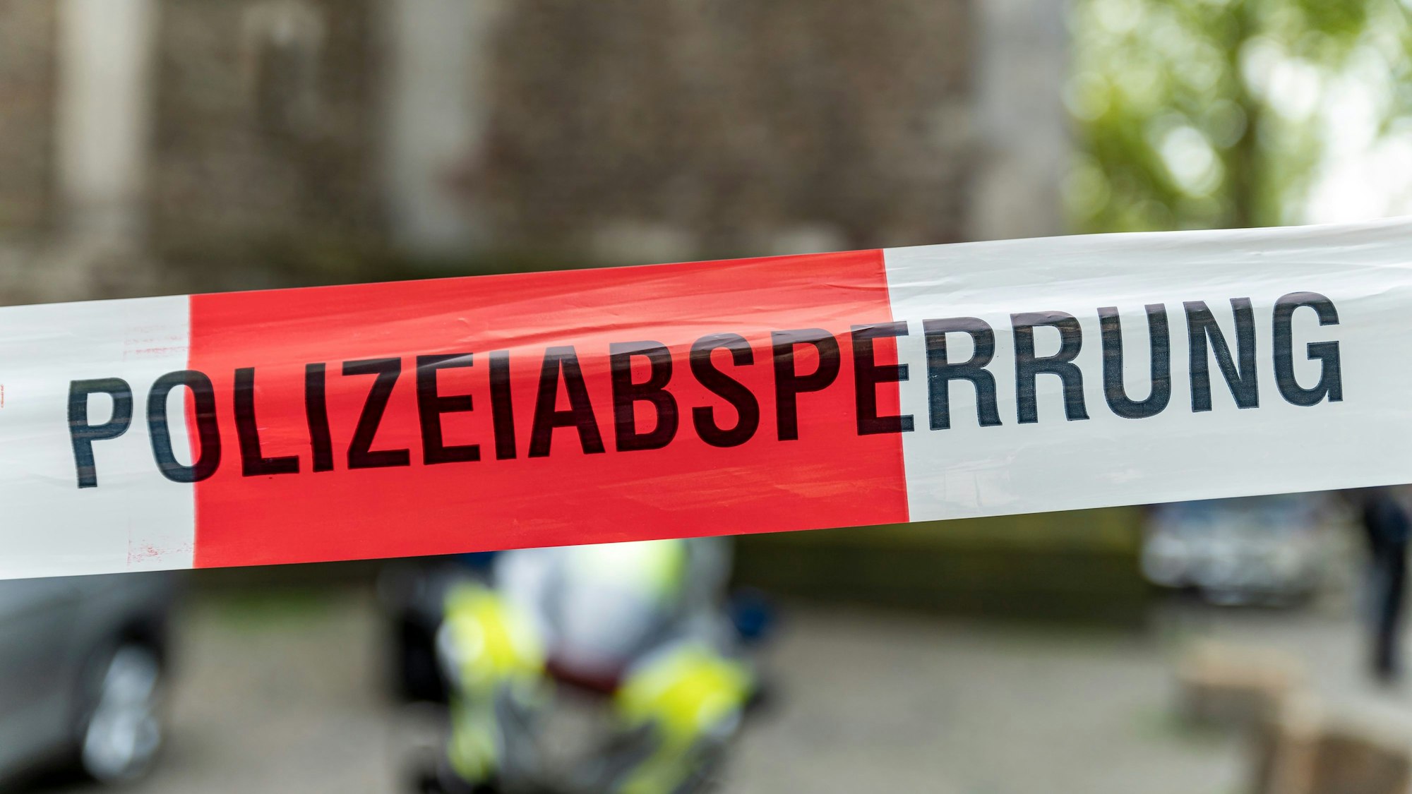 Ein mit Flatterband der Polizei NRW, dahinter ist verschwommen ein Polizei-Motorrad zu erkennen.