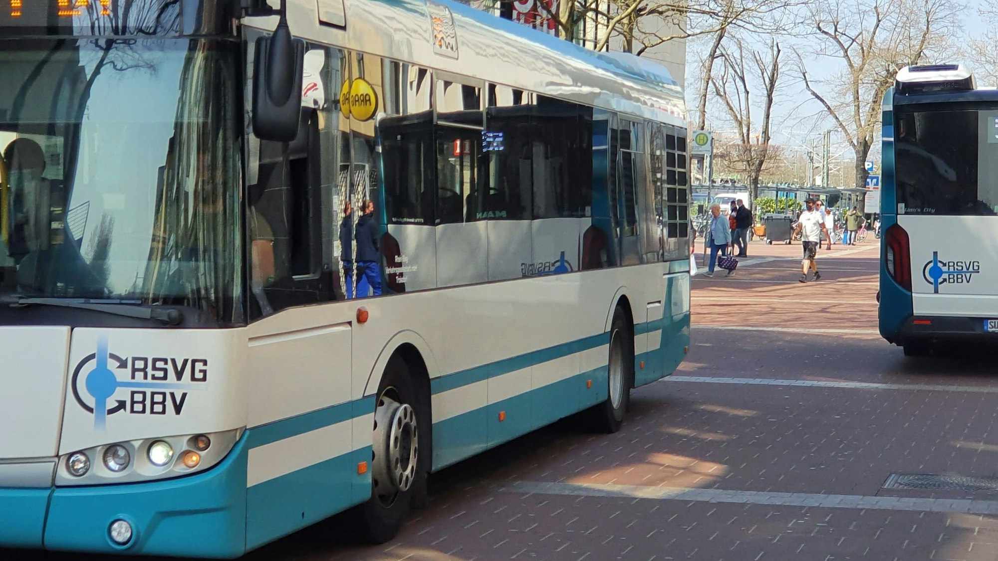 Zwei Busse fahren über eine rot gepflasterte Straße am Siegburger ICE-Bahnhof