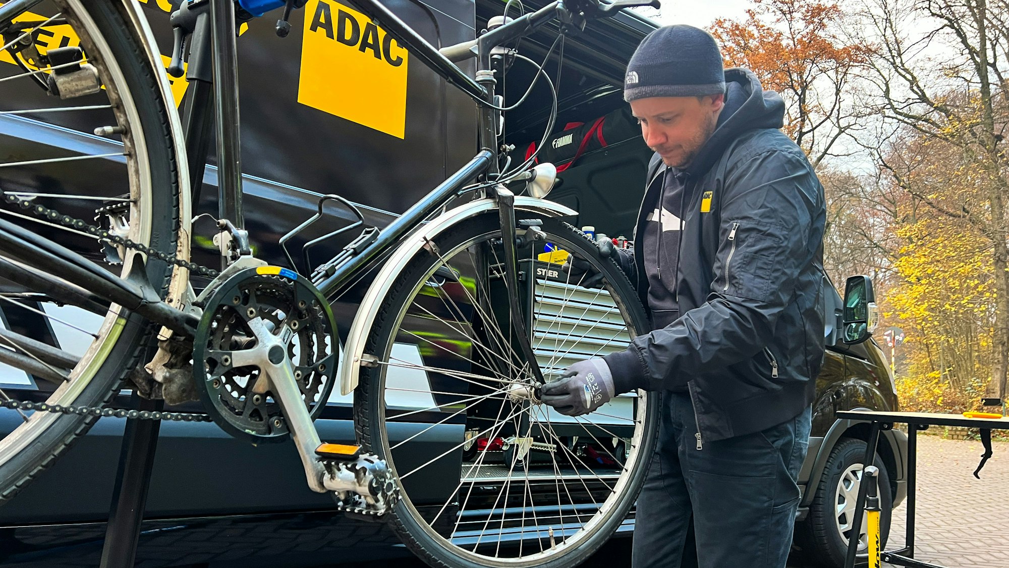 Andreas Kaurisch vom ADAC steht an seiner mobilen Fahrradwerkstatt. Auf einer Hebebühne ist ein Rad montiert.