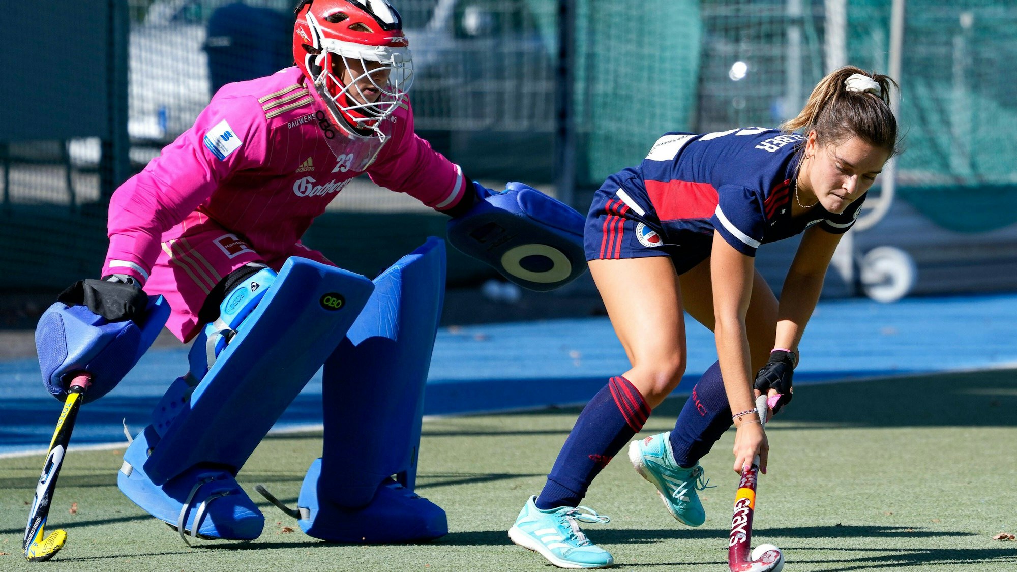 Eine Hockeytorhüterin versucht, ihre Gegenspielerin am Schuss zu hindern.