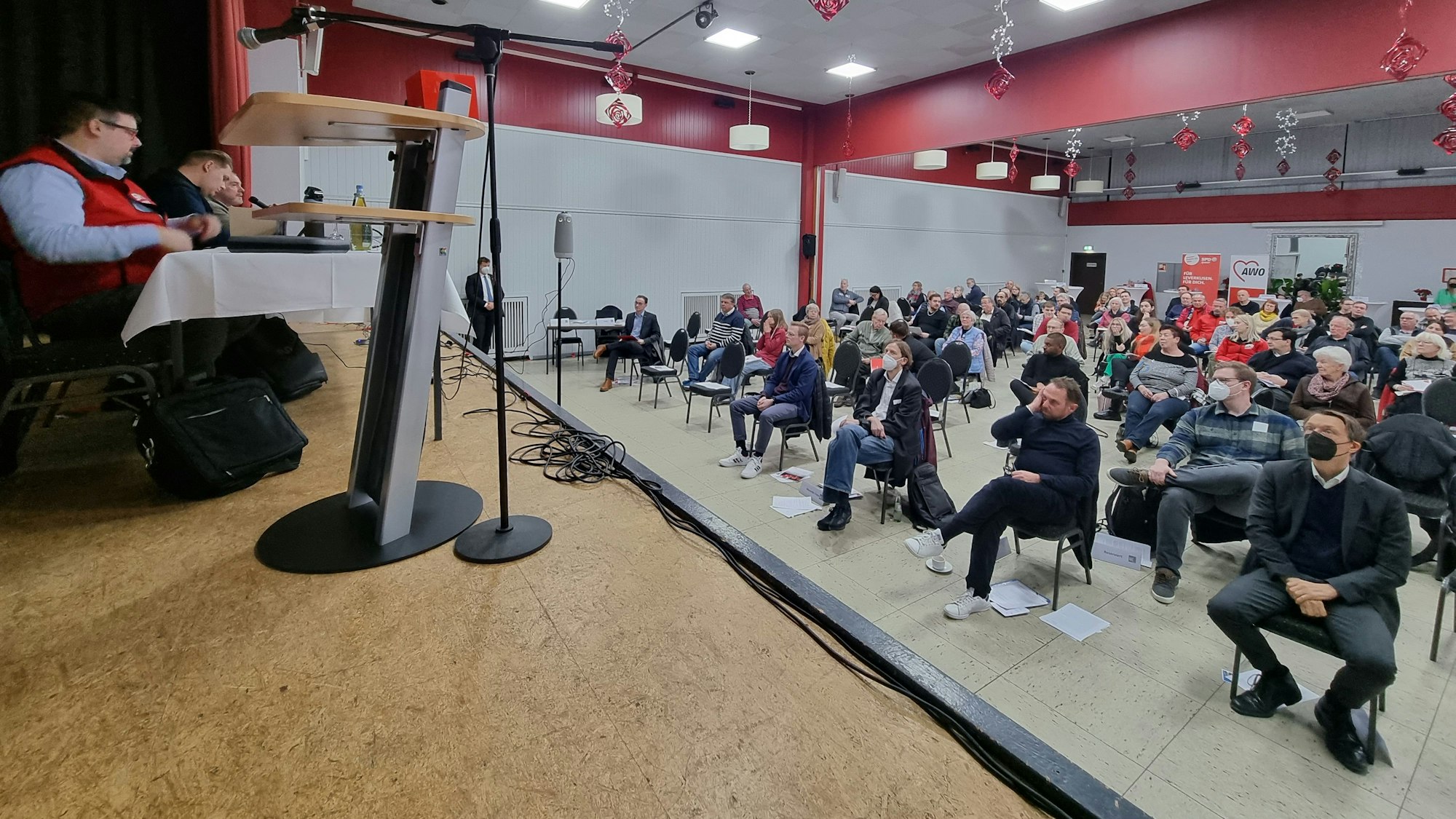 Mitglieder der SPD Leverkusen sitzen in einem großen Saal und schauen auf eine Bühne.