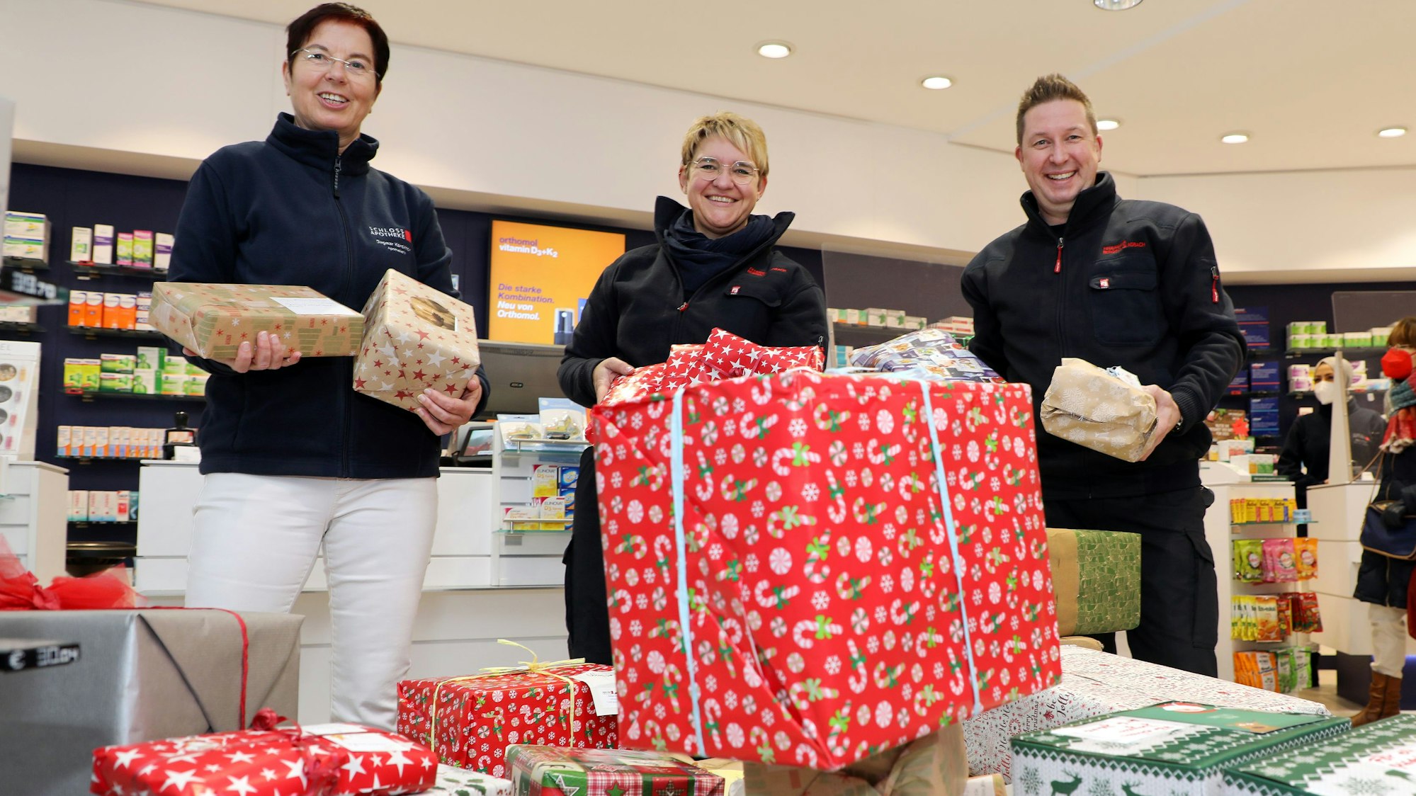 Mehrere Menschen stehen hinter einem Berg von Geschenken in der Bensberger Schloss- Apotheke.