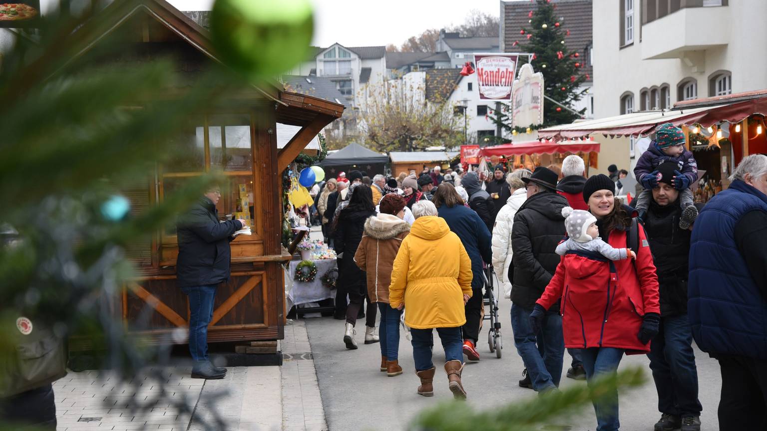 Blick auf den Vorplatz des Wiehler Rathauses, wo Menschen zwischen den Holzbunden flanieren.