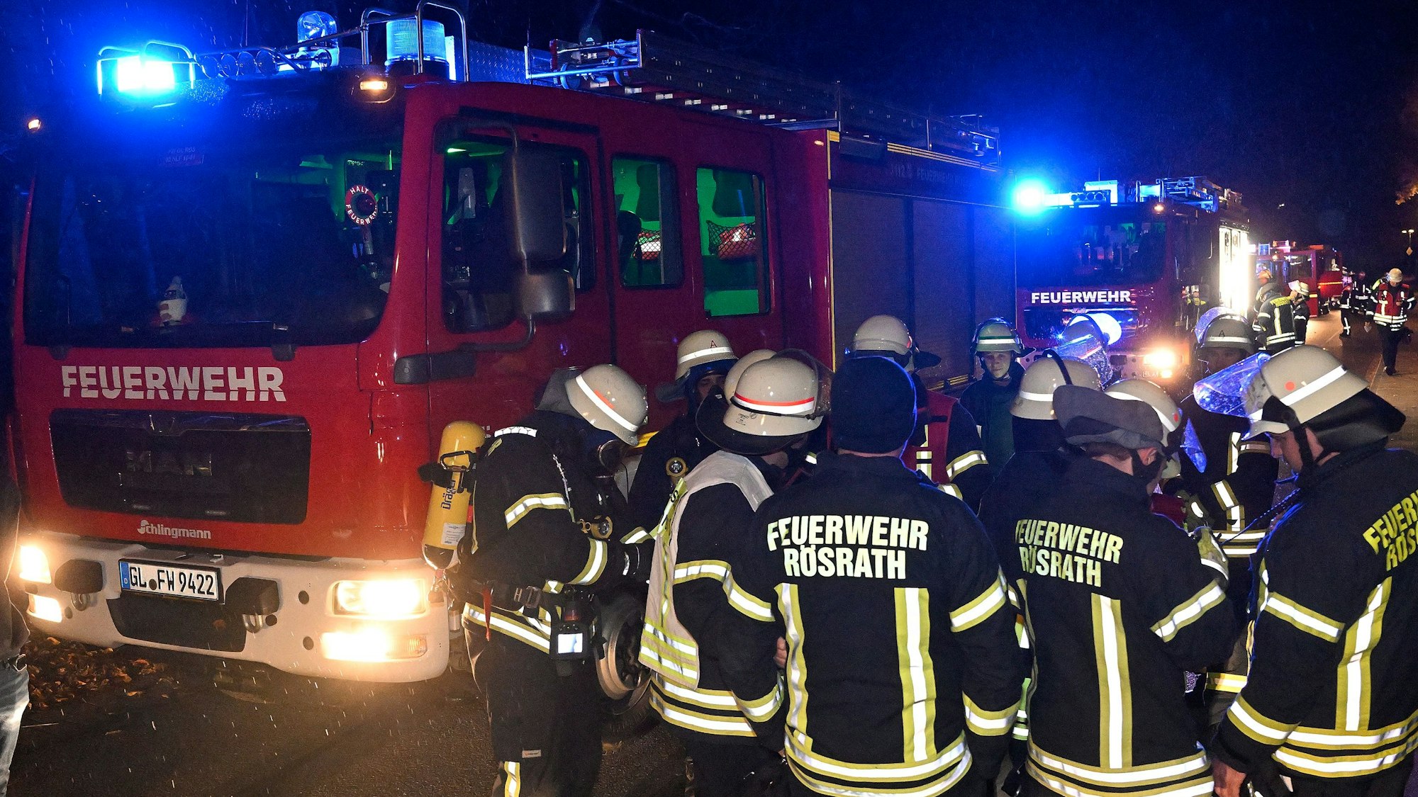 Feuerwehrleute stehen vor Einsatzfahrzeugen.