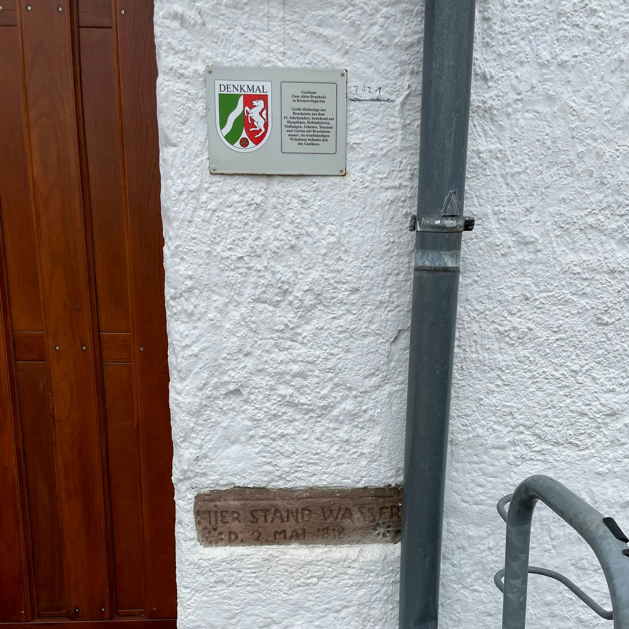 Mit Bleistift ist neben das Schild die Hochwassermarke vom 14. Juli gemalt.