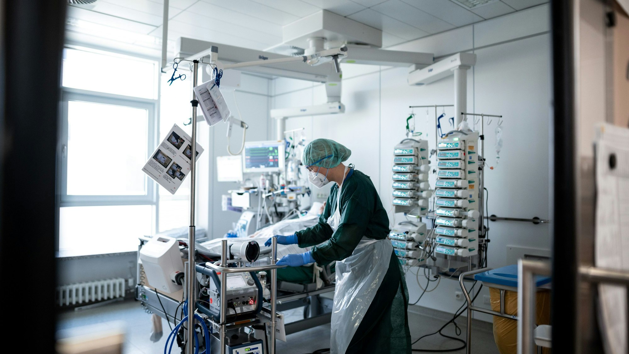 Eine Mitarbeiterin der Pflege steht in einem Zimmer der Corona-Intensivstation Eines Klinikums und bedient ein ECMO-Gerät, eine Herz-Lungen-Maschiene.