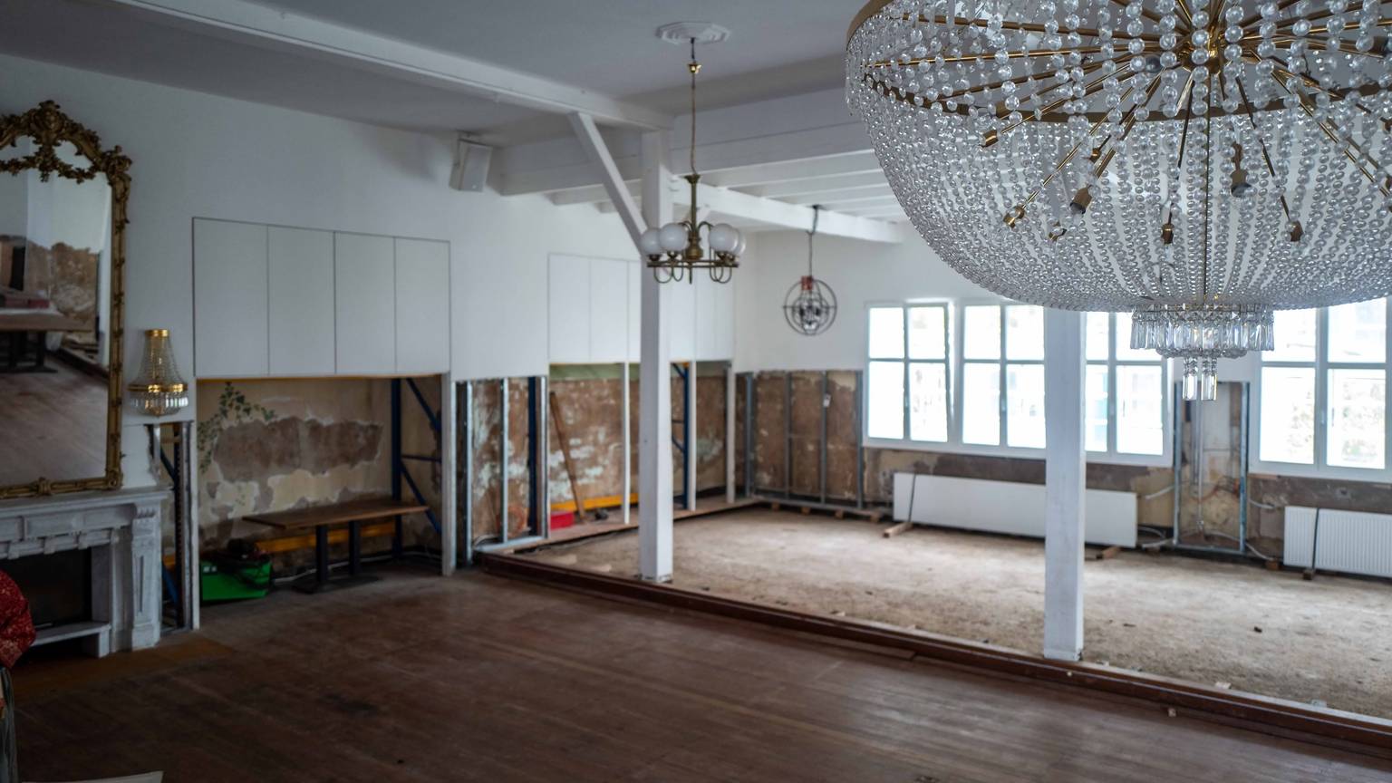 Im Saal des Brauhauses sind die Schäden, die die Flut verursacht hat, noch gut sichtbar. Im Vordergrund hängt ein Leuchter, im Hintergrund sind die Wände nach der Flut immer noch aufgerissen.