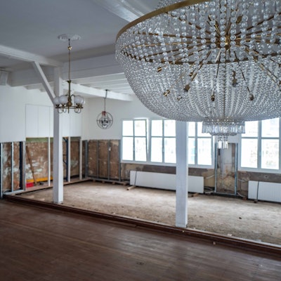 Im Saal des Brauhauses sind die Schäden, die die Flut verursacht hat, noch gut sichtbar. Im Vordergrund hängt ein Leuchter, im Hintergrund sind die Wände nach der Flut immer noch aufgerissen.