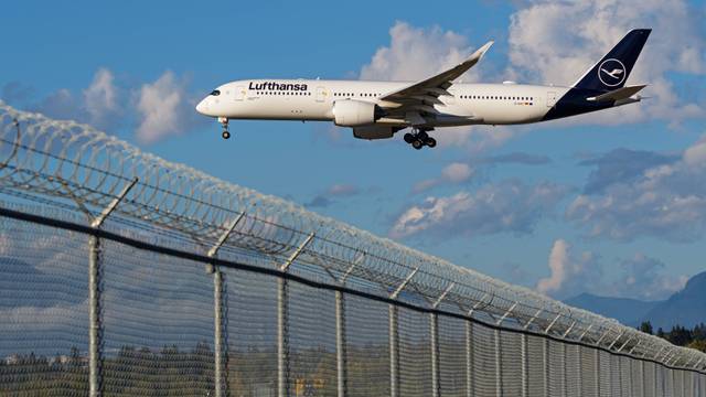 Ein A350-900-Flugzeug fliegt über einen Zaun.