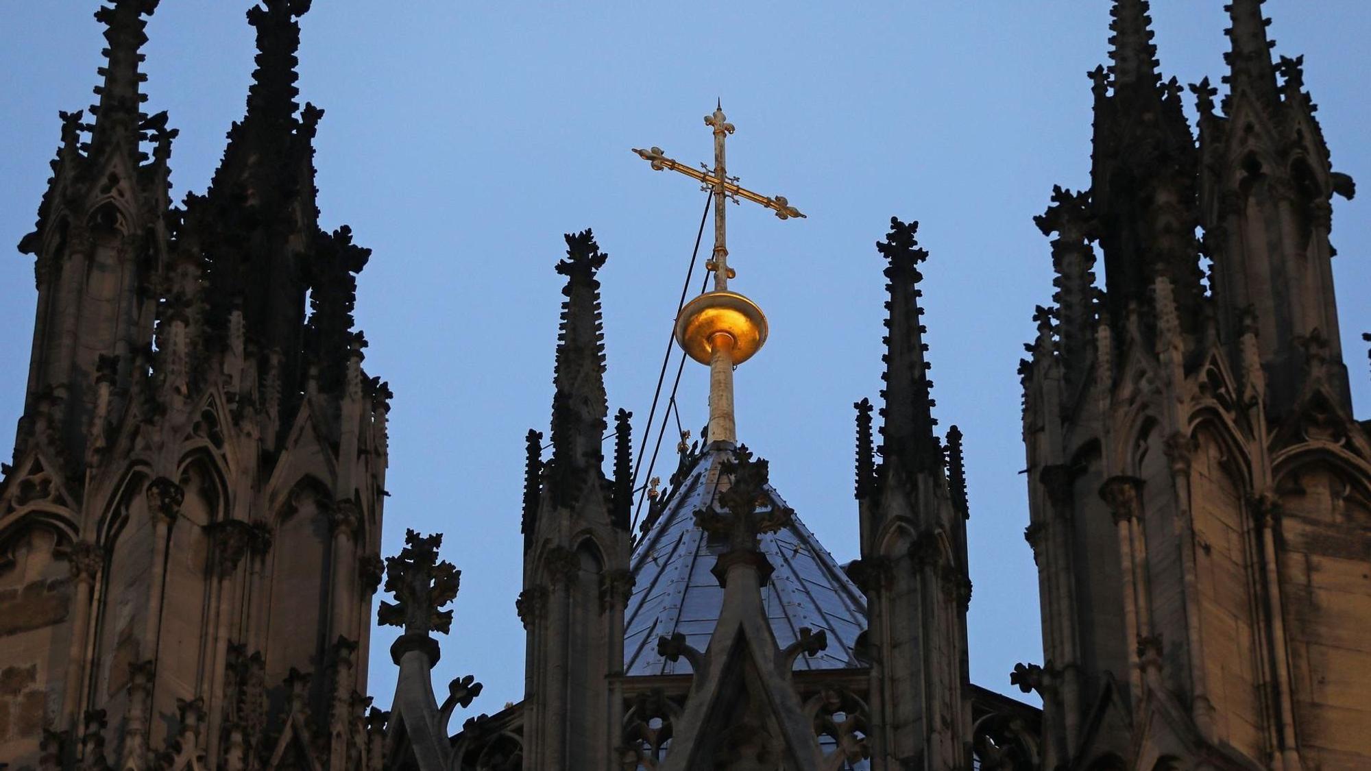 Ein Kreuz steht hinter dem Strebewerk am Dom.