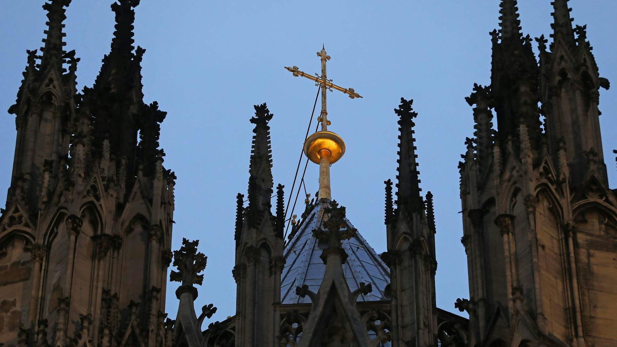Ein Kreuz steht hinter dem Strebewerk am Dom.