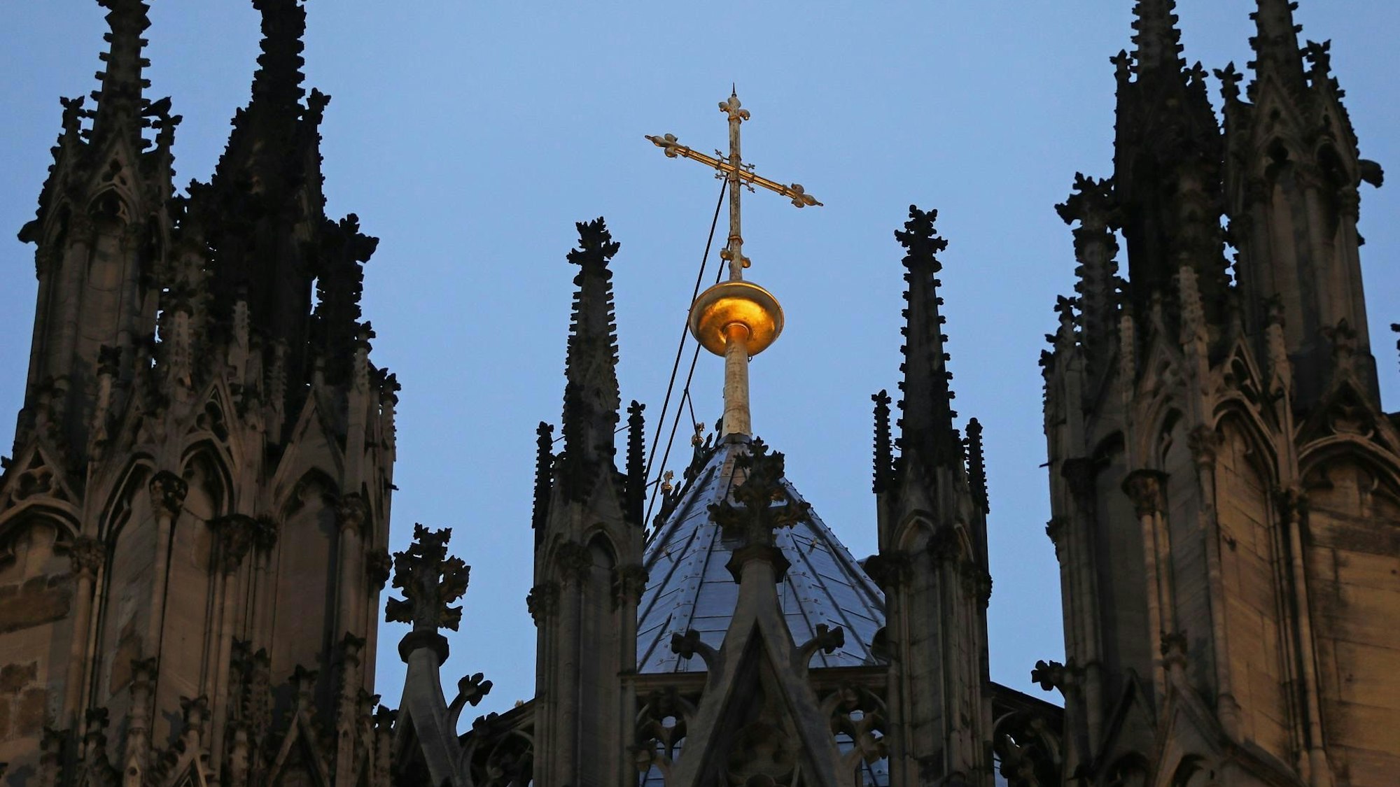 Köln: Ein Kreuz steht hinter dem Strebewerk am Kölner Dom (Archivbild).