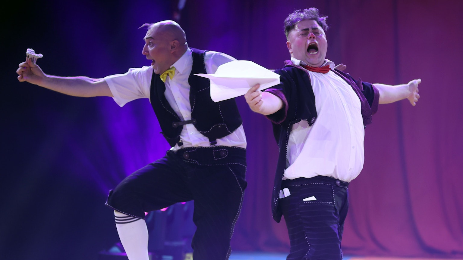 Zwei Clowns vom ukrainischen Trio Equivokee Clowns schneiden Grimassen beim Spielen mit Papierfliegern.