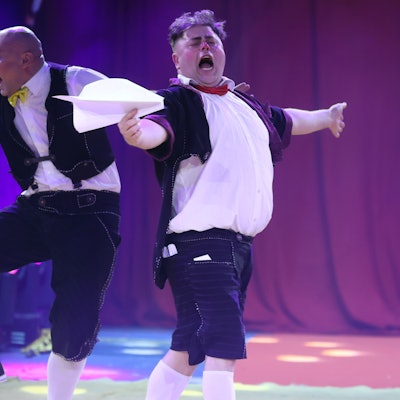 Zwei Clowns vom ukrainischen Trio Equivokee Clowns schneiden Grimassen beim Spielen mit Papierfliegern.