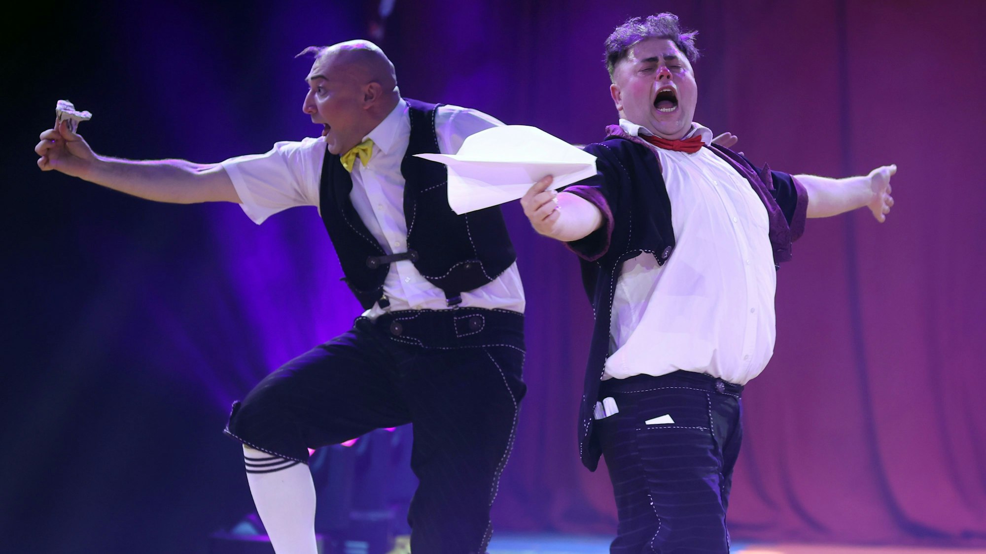 Zwei Clowns vom ukrainischen Trio Equivokee Clowns schneiden Grimassen beim Spielen mit Papierfliegern.